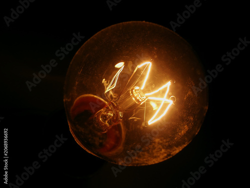 фотографія Vintage tungsten light bulb glowing warmly in complete darkness, symbolizing innovation, inspiration, creativity, hope, and the power of a single idea