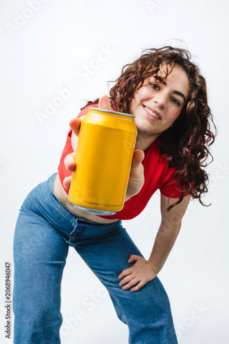 young hispanic woman holding and showing a soda refreshment can foreground