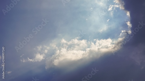 Foto Sunlight breaking through clouds in a bright blue sky.