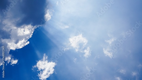 Foto Sunlight breaking through clouds in a bright blue sky.