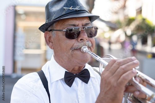 Sticker Mature adult musician wearing a fedora hat and sunglasses playing a brass trumpe