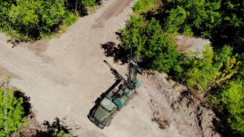 Aerial drone view of a mobile geotechnical drilling rig conducting soil investigation and ground sampling at a future construction site near a forested area in Sumy, Ukraine. The specialized drilling 
