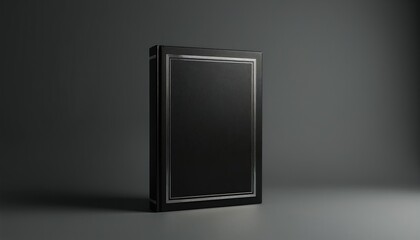 Black hardcover book with elegant silver frame borders stands on a dark grey studio background. Minimalist design for portfolio or presentation. Empty cover space for text. Clean pro look.