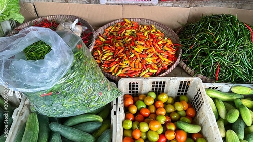 Bild auf Leinwand A vibrant display of fresh produce at a traditional market or grocery store, showcasing chilies, tomatoes, cucumbers and more