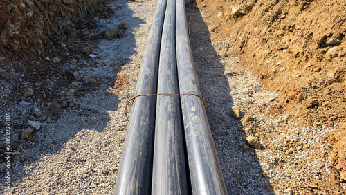 Quadro su tela High-angle perspective of a bundled plastic utility conduit run inside a gravel-