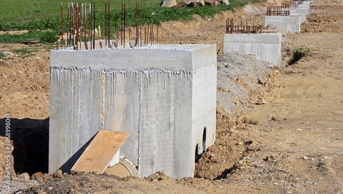 Foto Reinforced concrete foundation pillars with exposed steel rebar on excavated gro