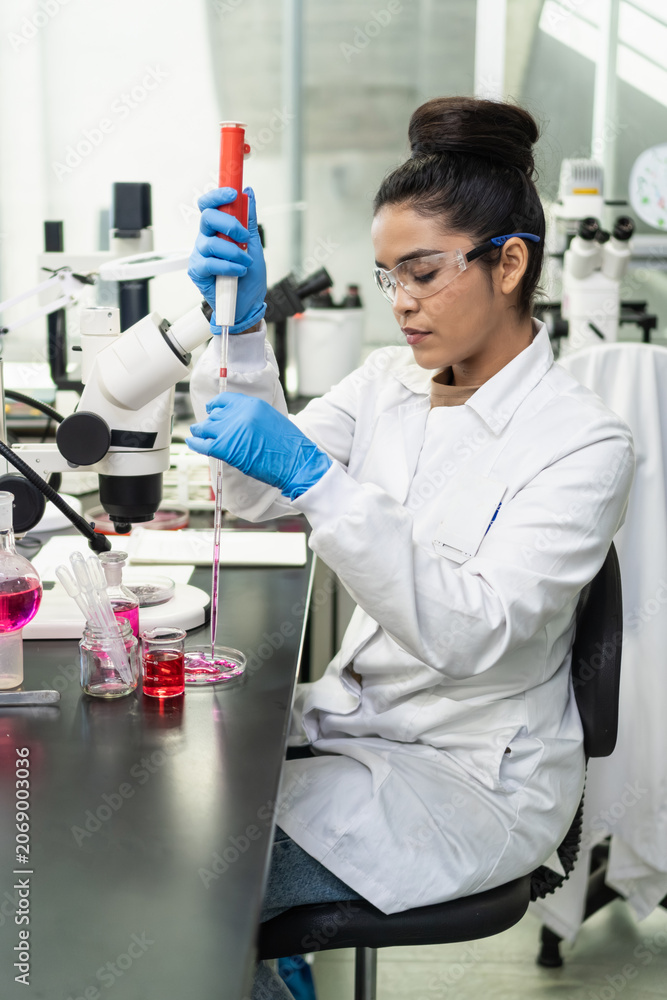 Fototapeta premium Female researcher pipetting liquid in biology laboratory