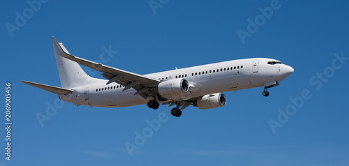 The plane lands, passenger airliner. The plane lands. Airplane, passengers flying in the blue sky, preparing to land at the airport