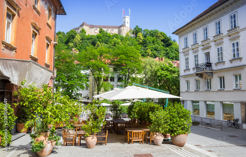 Ljubljana Castle sits atop a green hill overlooking an inviting outdoor cafe patio, Slovenia