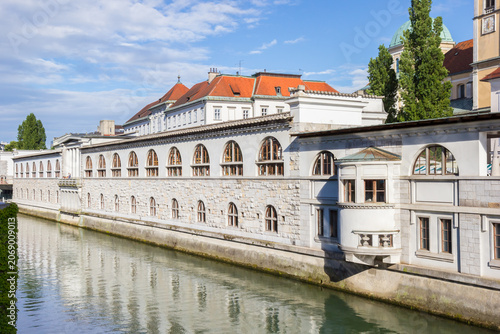 Long historic stone market building reflects on the river in Ljubljana, Slovenia