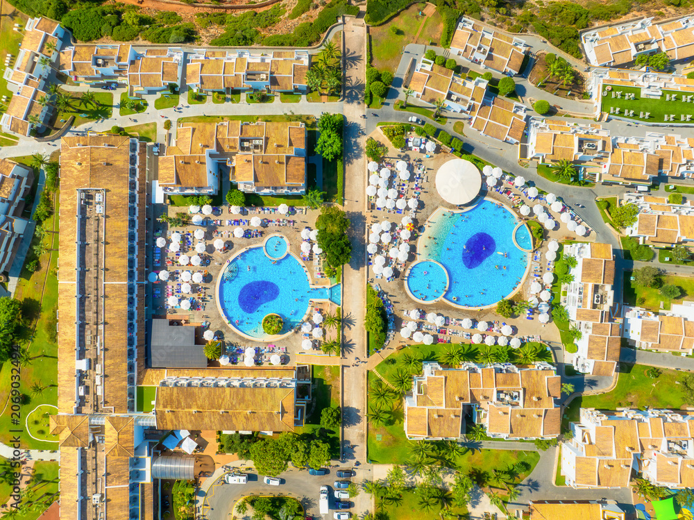 Obraz premium Aerial drone view of a modern residential neighborhood or resort area. Suburban streets with houses, hotel buildings, private swimming pools and people relaxing outdoors.