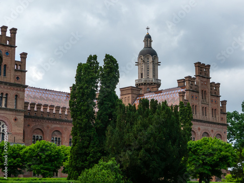 Chernivtsi University buildings stand among green trees in Chernivtsi, Ukraine on a cloudy day