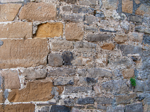 Stone wall showing different textures, colors and signs of wear at an old building site in daylight
