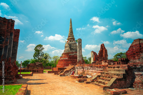 Ancient headless Buddha statues lining the red brick wall at Wat Mahathat in Ayutthaya, Thailand.