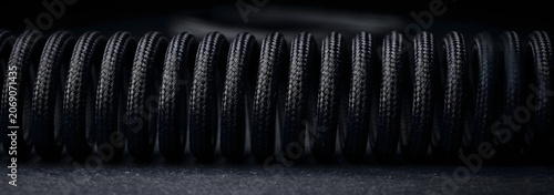Macro Shot of Black Braided Coil Cable on Dark Background.