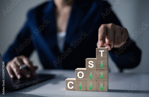 A businessman's hand with a wooden cube: business development concepts, cost reduction concepts, optimizing production management, reducing company expenses to maximize profits.