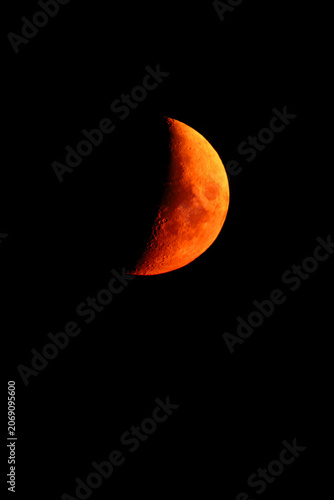 Quadro em tela Stunning close-up of a glowing orange crescent moon during a lunar event, set against a dark and clear night sky, highlighting the intricate details of craters and the lunar surface