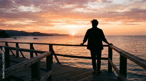 Silhouette of person on pier at sunset