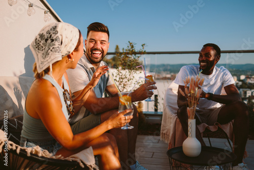 Foto Happy diverse friends enjoying drinks and conversation on a summer rooftop