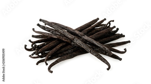 A pile of dried vanilla pods scattered on a flat surface, suggesting culinary use or aromatic properties