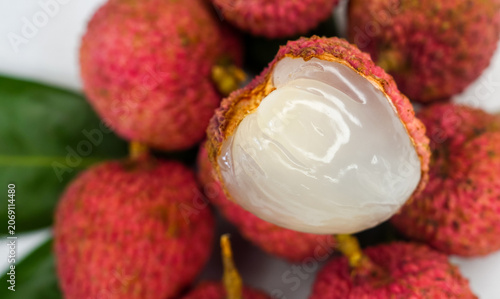 Close up of fresh red litchi or lychee with cut in half slice isolated on fruit background. Juicy lychee fruit with red skin, white flesh and green leaves, concept of tropical sweet fruits.