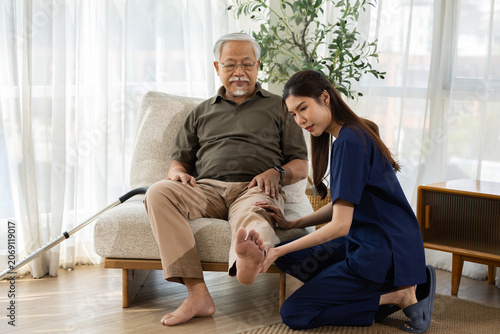 Elderly man caregiver foot care home care senior care nurse injury support living room patient, elderly man receiving foot care from caregiver living room, calm home health support after injury