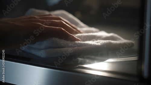 Person Cleaning Glass Surface with Soft White Cloth