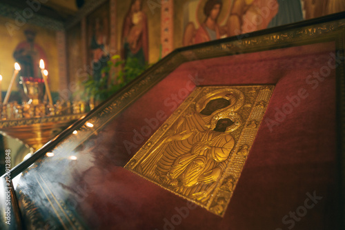 Valokuva Gilded Orthodox icon of the Virgin and Child in ornate glass display within a candlelit church interior, surrounded by rich Byzantine iconography and warm devotional ambiance
