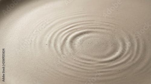 Closeup of concentric circular ripples on a textured beige surface