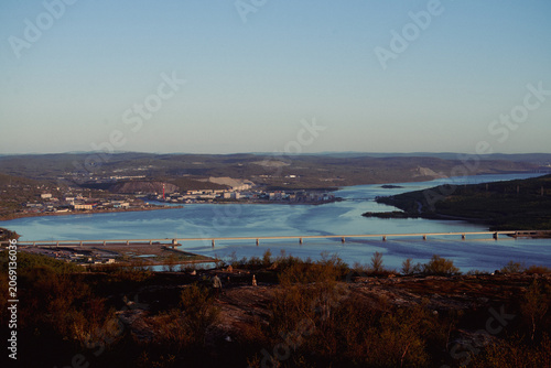 Coastal industrial town with river and bridge at dusk