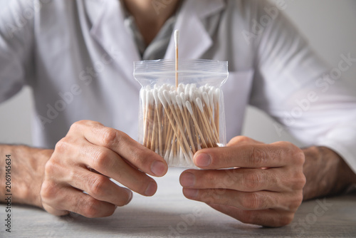Caucasian man showing cotton bud for ear cleaning.