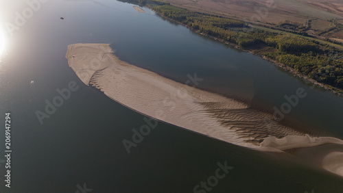 This aerial shot captures a stunning sandy island surrounded by tranquil waters, showcasing nature's beauty