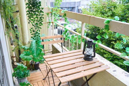 Cozy balcony surrounded by green plants and trees with table and chairs