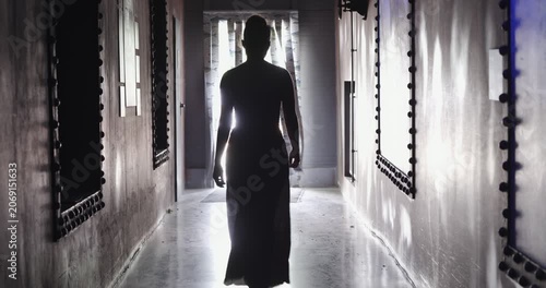 Woman silhouette walking down a dark hallway