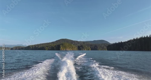 Vessel leaving wake on calm water past coastline