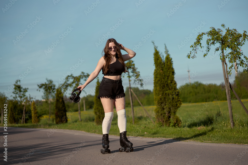 Fototapeta premium Skater enjoys a warm afternoon gliding on a peaceful country road surrounded by lush greenery