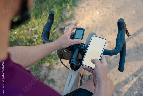Cyclist checking smartphone and cycling computer navigation on gravel route