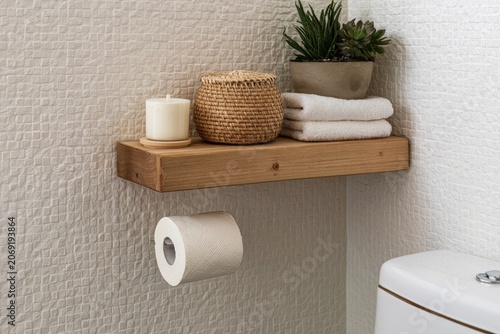 Rustic wooden shelf with candle, basket, towels, plant, and toilet paper