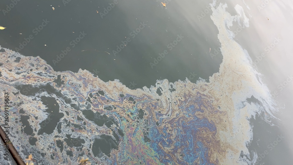 Naklejka premium Iridescent oil slick polluting dark water surface