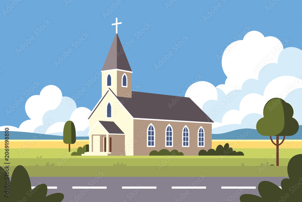 Naklejka premium Protestant or Catholic church building stands peacefully in a green field alongside a road under a blue sky with fluffy white clouds.