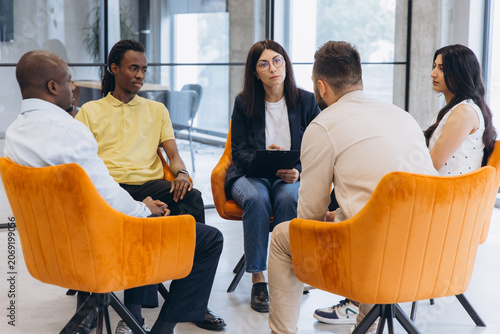 Foto Diverse people meeting in a support group, counselor facilitating discussion and