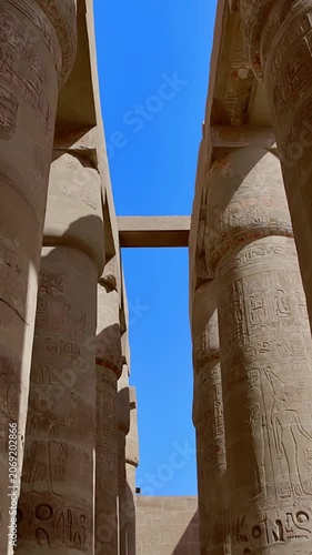 Karnak Temple in Luxor, Egypt. Massive hieroglyphic columns in Great Hypostyle Hall, Karnak Temple Luxor Egypt. Upward view of ancient carved pillars against blue sky.