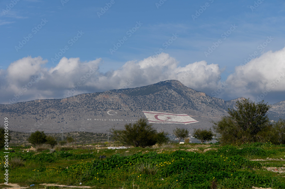 Fototapeta premium Majestic mountains adorned with flag in the serene landscape of Northern Cyprus
