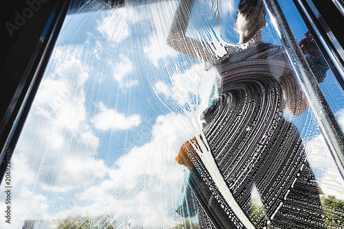 Foto Professional worker cleaning a glass window with squeegee and soapy water