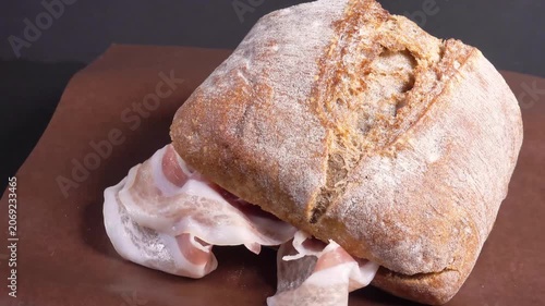 ciabatta sandwich with sliced ham, on paper, rotating