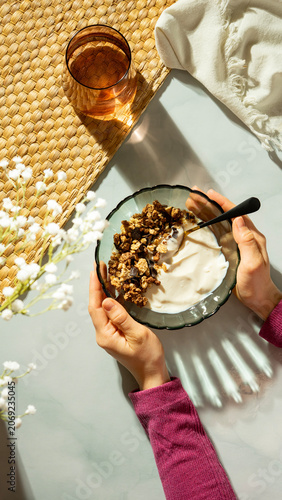 Person holding a bowl of yogurt with granola