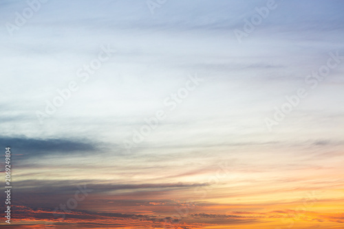 Colorful sunset sky with soft clouds and warm orange, pink and blue tones. Natural background ideal for travel, nature, weather and design projects.