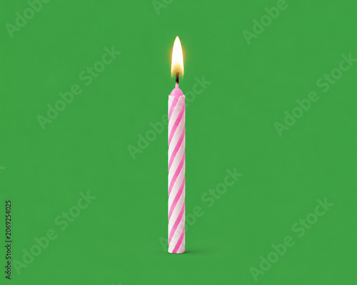 Lit pink and white striped birthday candle with a bright flame on a solid green background