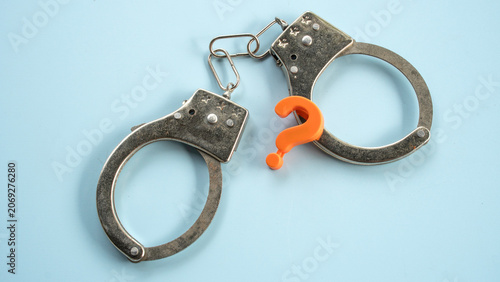 Photos Steel metal handcuffs with orange question mark on plain background