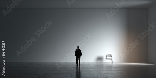Lone figure stands illuminated in minimalist space with chair shadow
